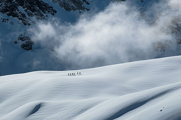 Gruppe überquert Gletscher, Sonne, Wolken, Schnee. © Maximilian Ihlenburg