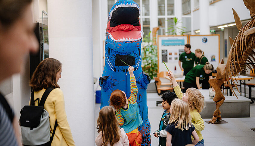 Kinder mit Student im Dinokostüm. Foto: Walter Skokanitsch