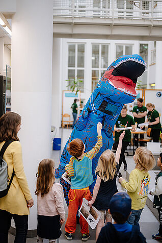 Kinder und ein Studierender in Dino-Kostüm