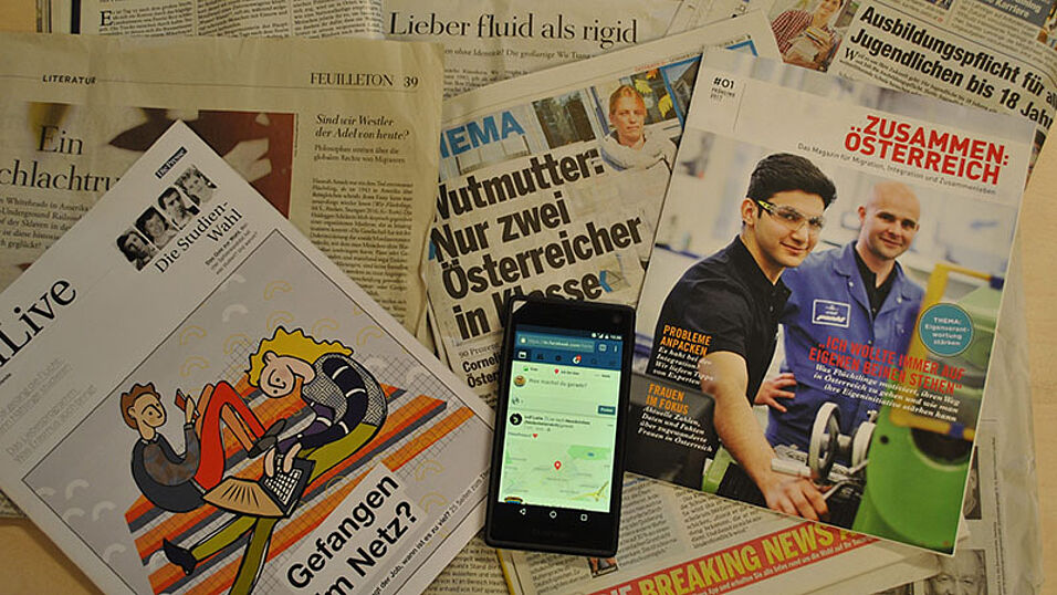 Diverse Zeitungen und ein Mobiltelefon mit Schlagzeilen zu Identitäten